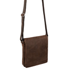 Small vertical brown leather messenger bag with long shoulder strap hanging side angle